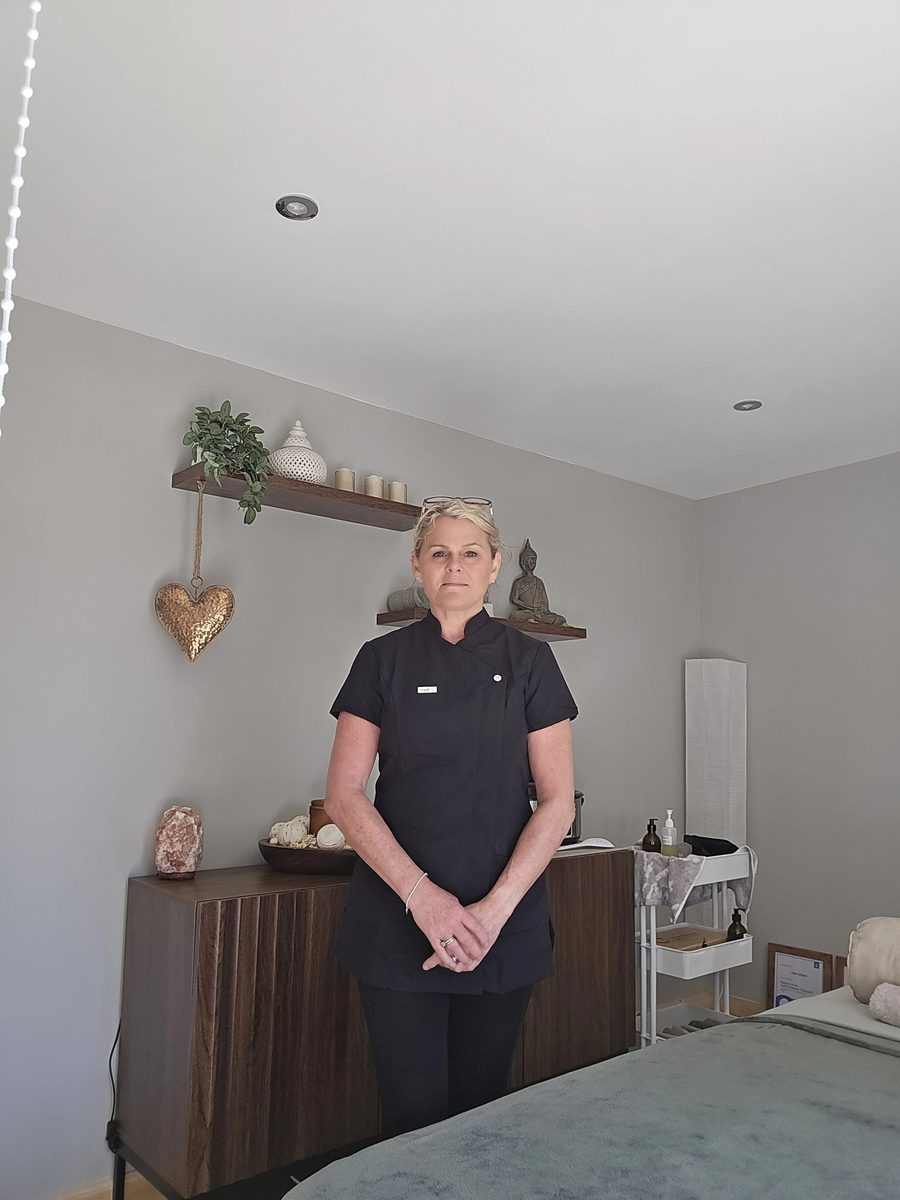 Jules standing in the Mantrana treatment room beside the heated massage bed