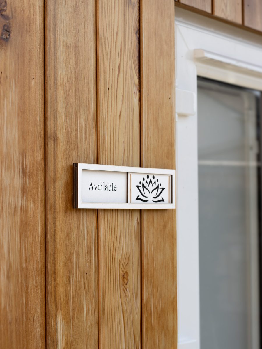 A small wooden Available sign with a lotus on the cabin's timber cladding